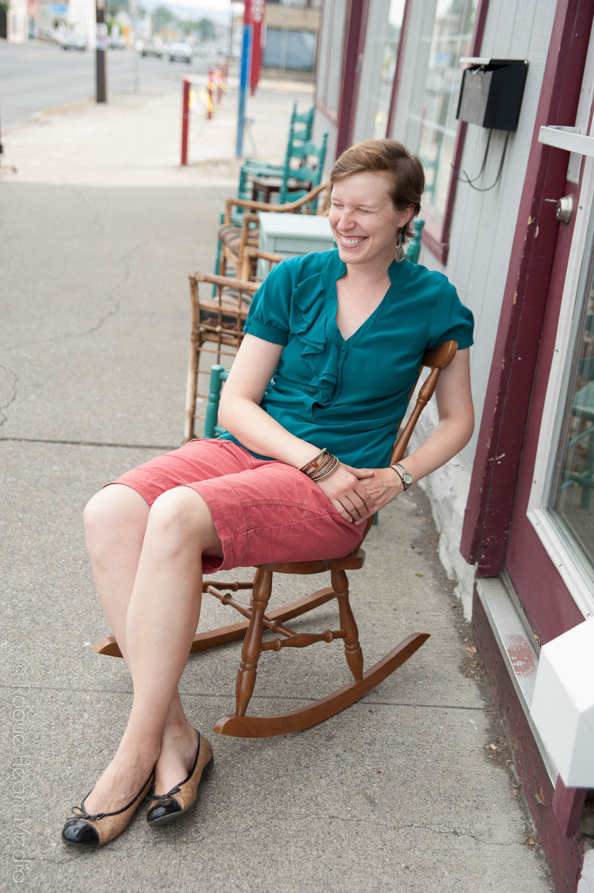 Annie laughing in a rocking chair outside of a vintage shop on Monroe